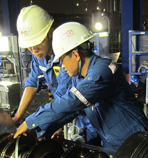 Two workers work on turbomachinery.